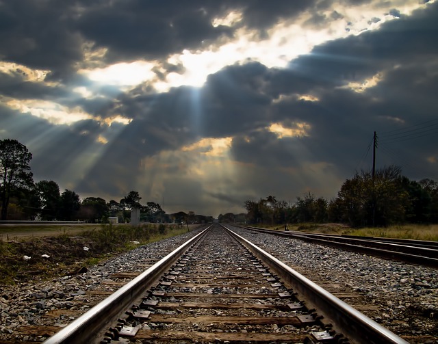 train tracks leading into the distance, sunlight through the clouds